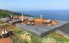 Terraces surrounded by vegetation and a view over the sea.